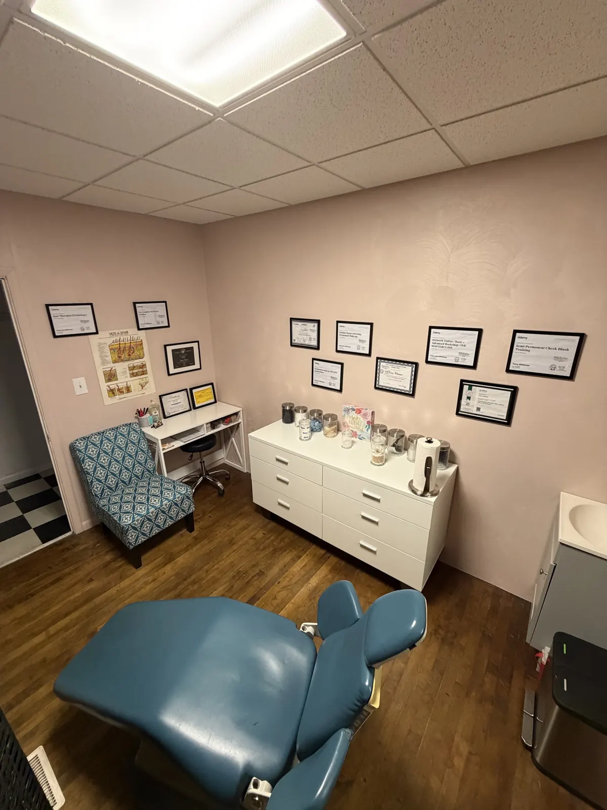 Treatment room with a teal treatment chair and framed certificates on the wall